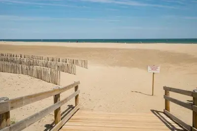 a sandy beach with a sign on it and a fence at Vagues et Vignes Gruissan Corbières in Gruissan