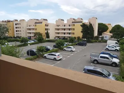 a parking lot with cars parked in front of buildings at Vagues et Vignes Gruissan Corbières in Gruissan