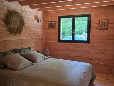 a bedroom with a bed in a log cabin at Chalet Lac de la Raviège la Laurinette SPA in Anglès