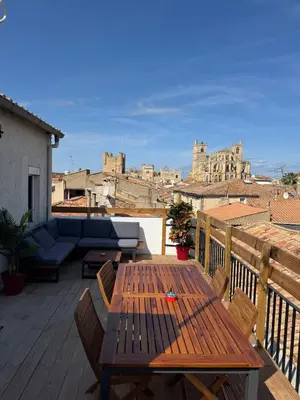 a wooden table on a balcony with a view of a city at Au cœur de l'histoire in Narbonne