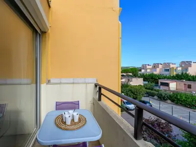 a table on a balcony with a cake on it at Apartment Gruissan Port-5 by Interhome in Gruissan