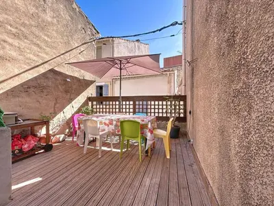 a wooden deck with a table and chairs and an umbrella at L'Espert - Appartement avec Terrasse in Gruissan