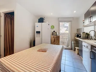 a kitchen with a white refrigerator and a table at L'Espert - Appartement avec Terrasse in Gruissan
