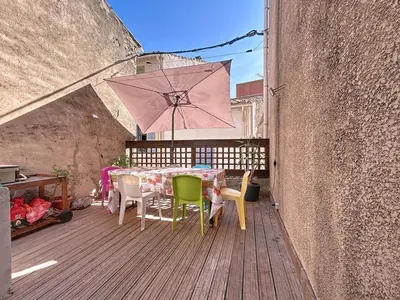 a patio with a table and chairs and an umbrella at L'Espert - Appartement avec Terrasse in Gruissan
