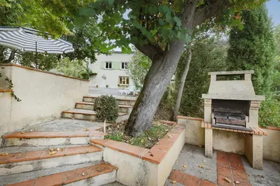 an outdoor patio with a fireplace next to a tree at Le Refuge du Tarn - Grand Jardin in Puylaurens