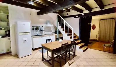 a kitchen and dining room with a table and a refrigerator at La Dolce Vista et sa terrasse privée avec vue in Revel