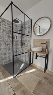 a bathroom with a shower with a sink and a mirror at Appartement en maison d'hôtes in Badens