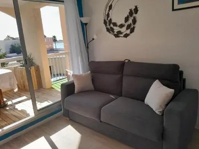 a living room with a couch and a sliding glass door at Joli appartement climatisé résidence avec piscine et plage du Grazel à 180m in Gruissan