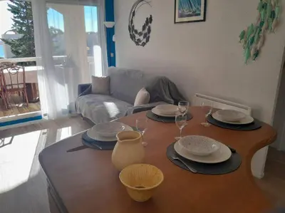 a living room with a table with plates and wine glasses at Joli appartement climatisé résidence avec piscine et plage du Grazel à 180m in Gruissan
