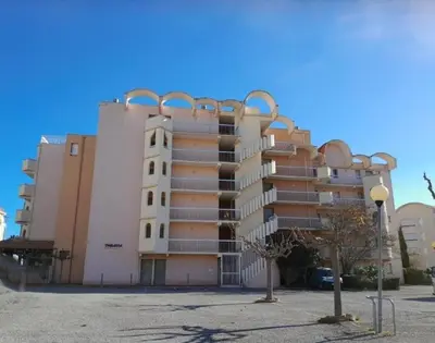 a large apartment building in front of a parking lot at Joli appartement climatisé résidence avec piscine et plage du Grazel à 180m in Gruissan