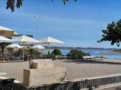 a beach with tables and umbrellas and a body of water at Joli appartement climatisé résidence avec piscine et plage du Grazel à 180m in Gruissan