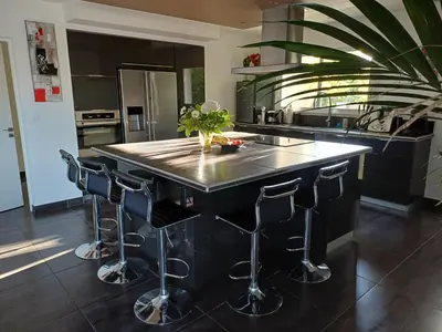 a kitchen with a large island with bar stools at Villa d'architecte avec piscine chauffée, 4 chambres, à 30 mn Gruissan plage in Sallèles-dʼAude