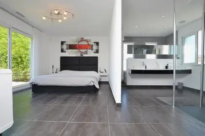a white bedroom with a bed and a bathroom at Villa d'architecte avec piscine chauffée, 4 chambres, à 30 mn Gruissan plage in Sallèles-dʼAude