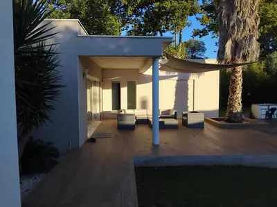 a patio with chairs and a hammock on a house at Villa d'architecte avec piscine chauffée, 4 chambres, à 30 mn Gruissan plage in Sallèles-dʼAude