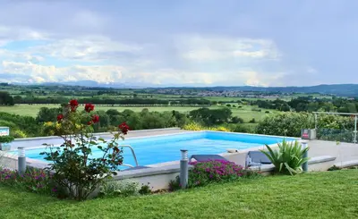 a swimming pool in a yard with flowers at B&B-Les Balcons de Maragon in Carcassonne