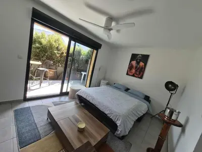 a bedroom with a bed and a table and a window at Confortable appartement rez de jardin- terrasse - parking in Narbonne