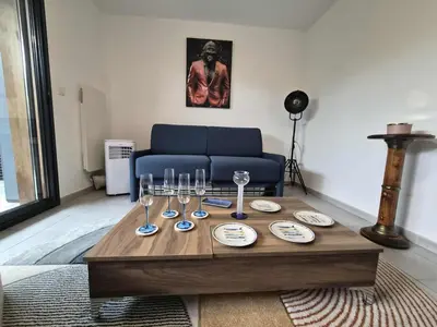 a living room with a table with glasses and a couch at Confortable appartement rez de jardin- terrasse - parking in Narbonne