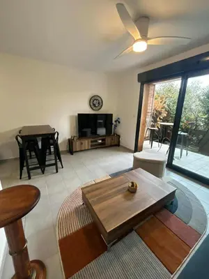 a living room with a ceiling fan and a table at Confortable appartement rez de jardin- terrasse - parking in Narbonne