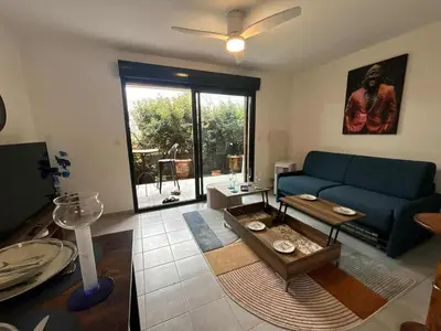 a living room with a blue couch and a table at Confortable appartement rez de jardin- terrasse - parking in Narbonne