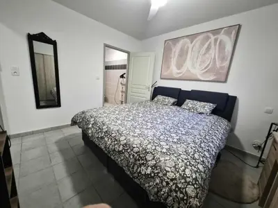 a bedroom with a bed and a painting on the wall at Confortable appartement rez de jardin- terrasse - parking in Narbonne