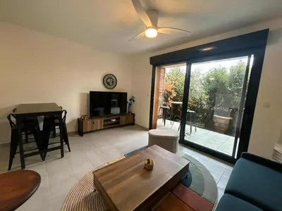 a living room with a television and a table at Confortable appartement rez de jardin- terrasse - parking in Narbonne