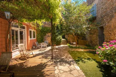 a backyard with a wooden deck with chairs and trees at Lagrasse Romantic house, enclosed garden, pool in Lagrasse