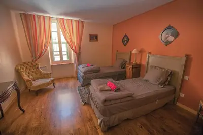 a bedroom with two beds and a chair at Lagrasse Romantic house, enclosed garden, pool in Lagrasse