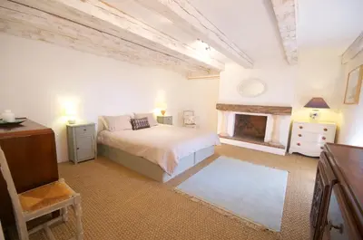 a white bedroom with a bed and a fireplace at Maison Tranquil in Bellegarde-du-Razès