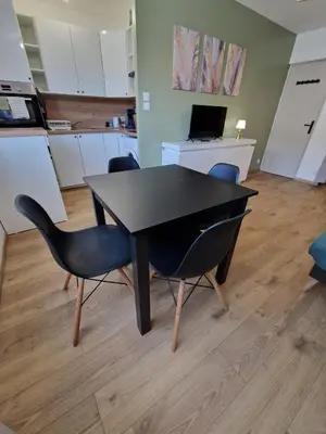 a dining room with a black table and chairs at Appartement confort accès direct plage in Port-la-Nouvelle