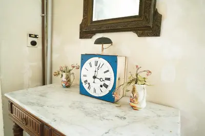 a clock sitting on top of a counter with a mirror at CAR-Volterra Cottage-AN in Carcassonne