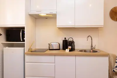 a kitchen with white cabinets and a sink at Le Petit Capoine 3 - T2 en plein centre de Carcassonne in Carcassonne