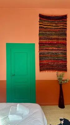 a bedroom with a green door and a colorful wall at La Casa De Frida charme & poésie in Narbonne