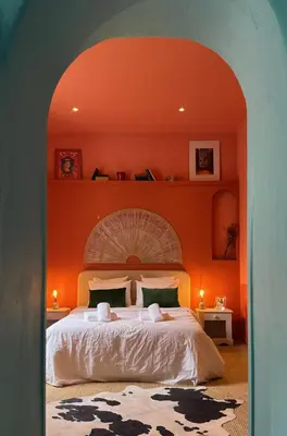 a bedroom with a large bed with an orange wall at La Casa De Frida charme & poésie in Narbonne