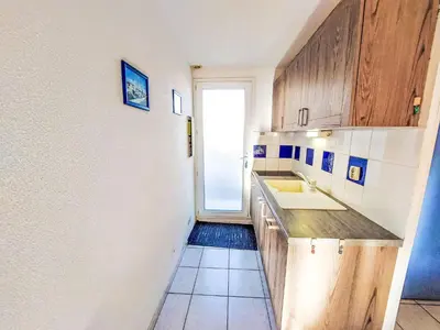 a small kitchen with wooden cabinets and a sink at Holiday Home Bora Bora 2-3 by Interhome in Gruissan