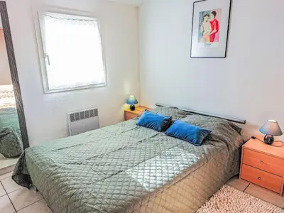 a bedroom with a bed with blue pillows and a window at Holiday Home Bora Bora 2-3 by Interhome in Gruissan