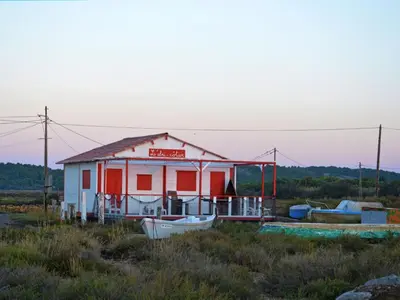 a small shack with a boat in a field at Holiday Home Bora Bora 2-3 by Interhome in Gruissan