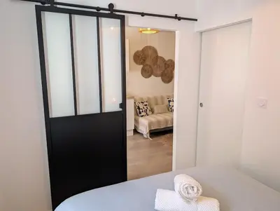 a bedroom with a black door and a living room at Le Petit Capoine 2- T2 Plein Centre de Carcassonne- in Carcassonne