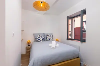a bedroom with a bed and a large window at Le Petit Capoine 2- T2 Plein Centre de Carcassonne- in Carcassonne