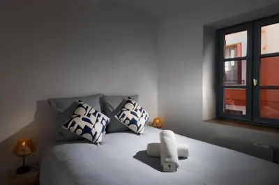 a bed with blue and white pillows and a window at Le Petit Capoine 2- T2 Plein Centre de Carcassonne- in Carcassonne