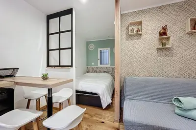 a small bedroom with a bed and a table and chairs at Charming studio in the city center of Narbonne in Narbonne
