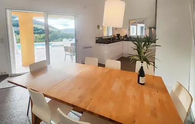 a dining room table with a bottle of wine on it at Awesome Home In Roquebrun in Roquebrun