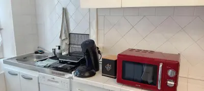 a red microwave sitting on a counter in a kitchen at Maison de village in Sigean