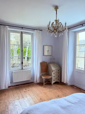 a bedroom with a large bed with two windows at La Maison Carrée - Escape to Timeless French Charm in Chalabre