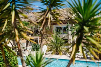 a house with a swimming pool and palm trees at La Villa Narbo Martius in Ornaisons