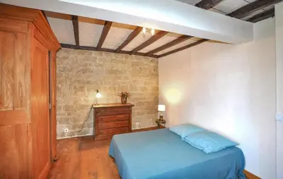 a bedroom with a blue bed and a brick wall at Apaisante Maison Authentique in Sainte-Foi