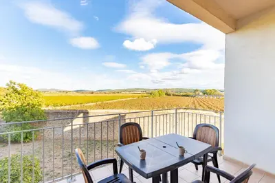 a balcony with a table and chairs and a view of a vineyard at Le Cosy Vignes - Piscine partagée in Azille