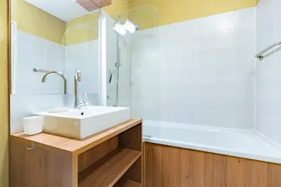 a bathroom with a white sink and a tub at Le Cosy Vignes - Piscine partagée in Azille