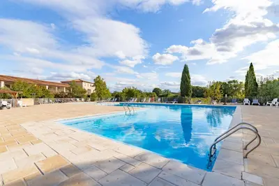 a large swimming pool with blue water at Le Cosy Vignes - Piscine partagée in Azille