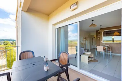 a dining room with a table and chairs and a balcony at Le Cosy Vignes - Piscine partagée in Azille