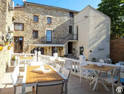 a patio with tables and chairs and a building at La maison millesime in La Caunette